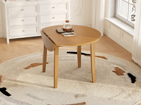 Extendable round solid wood dining table by Anthony & Home, showing the polished surface and sturdy legs in a modern studio setting.