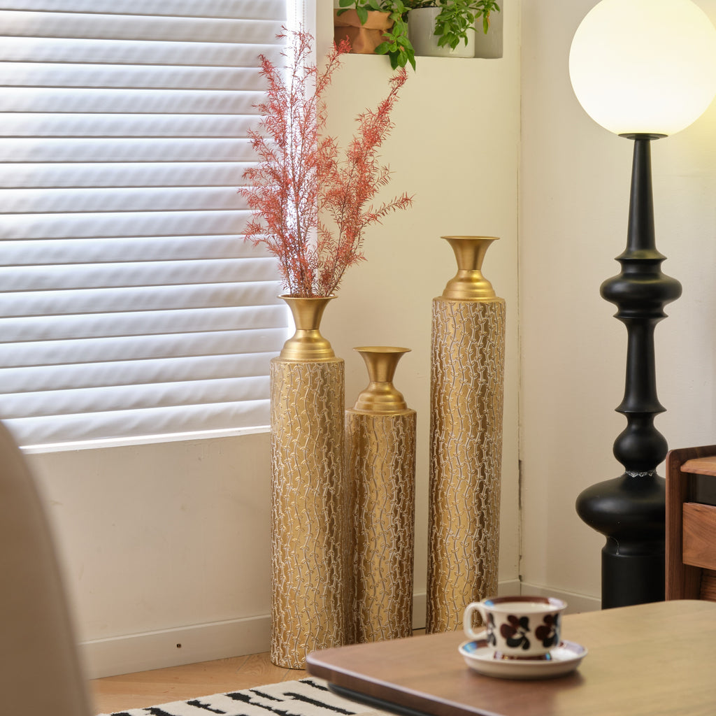 Set of three Anthony & Home Heritage Collection gold distressed metal vases with vine pattern for living room decor.
