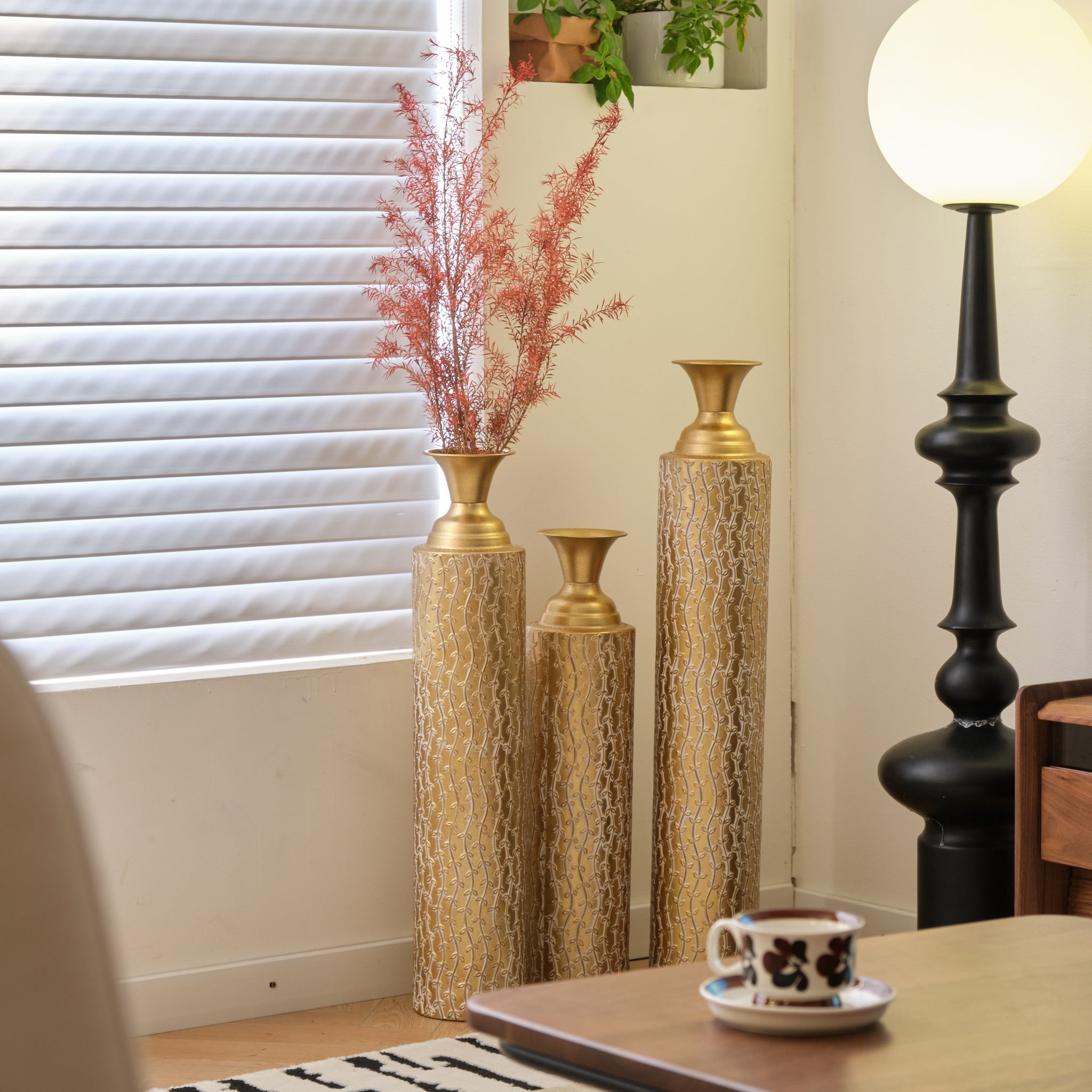 Set of three Anthony & Home Heritage Collection gold distressed metal vases with vine pattern for living room decor.