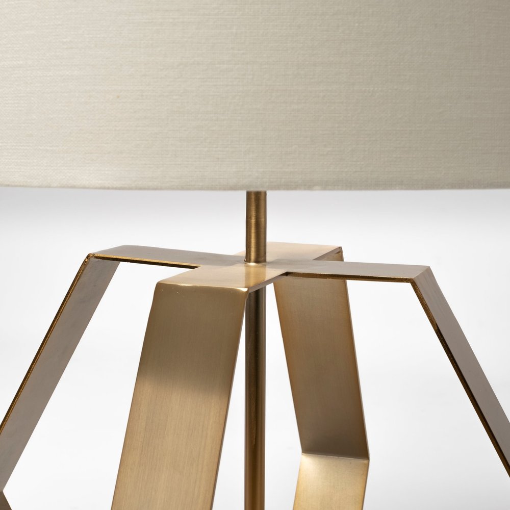 HomeRoots gold geometric design table lamp with a modern, angular base and a sleek lampshade on a wooden table.