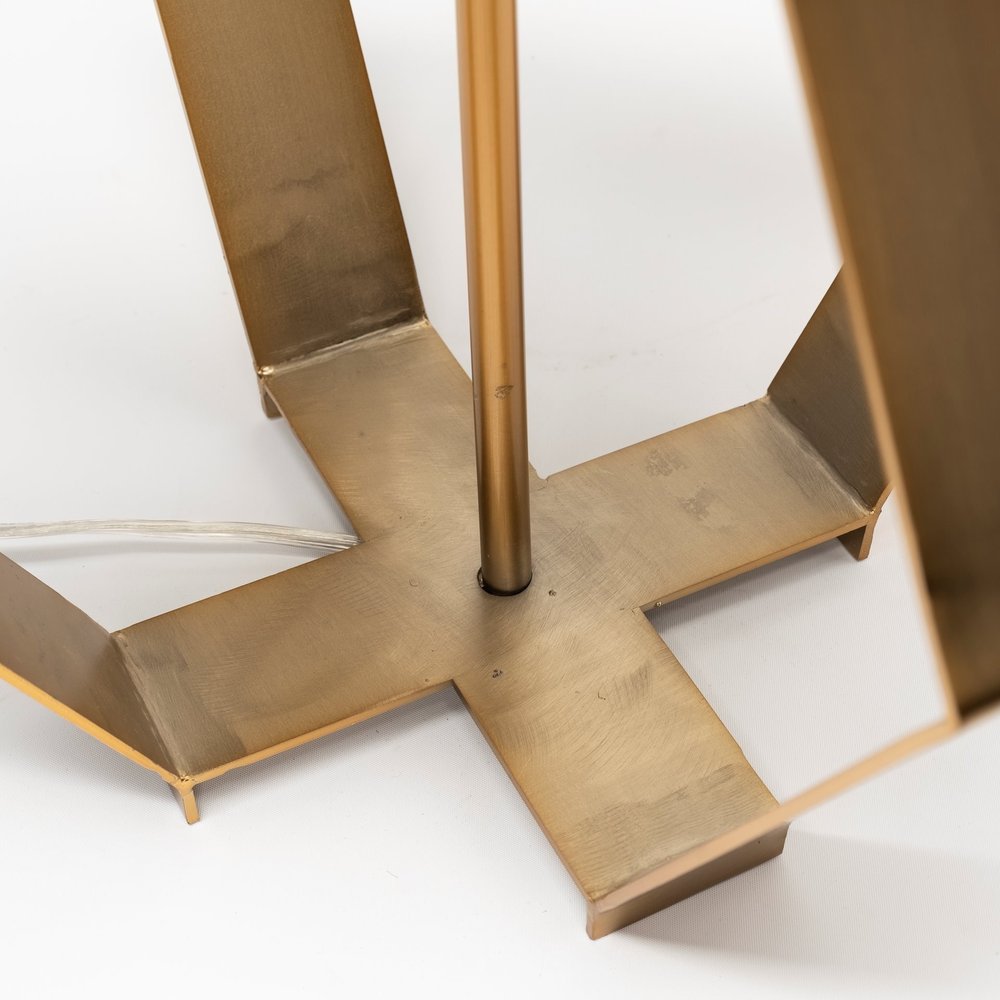 Gold geometric design table lamp by HomeRoots with a modern, stylish base and a neutral lampshade on a wooden table.