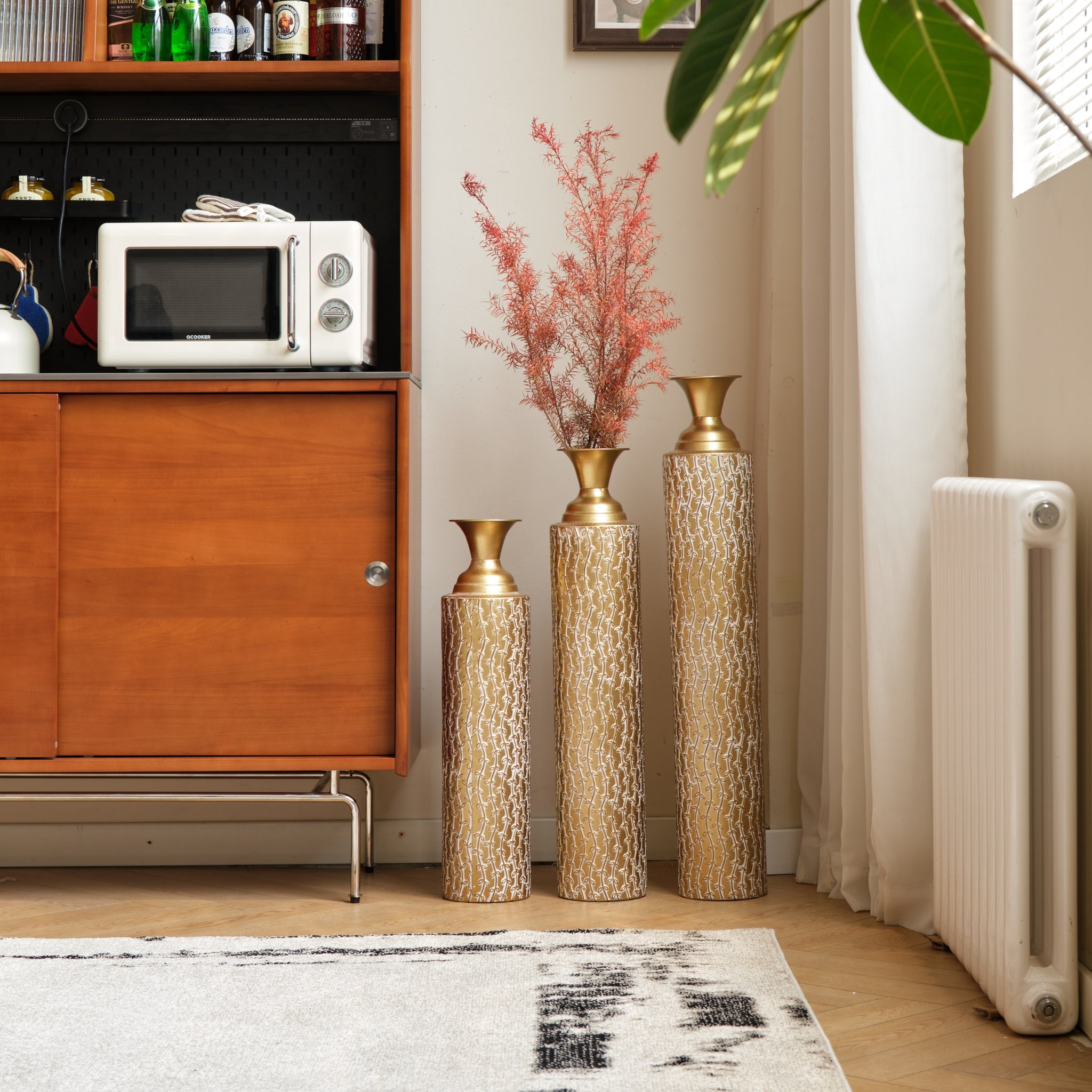 Set of three Anthony & Home Heritage Collection gold distressed metal vases with vine pattern for living room decor.