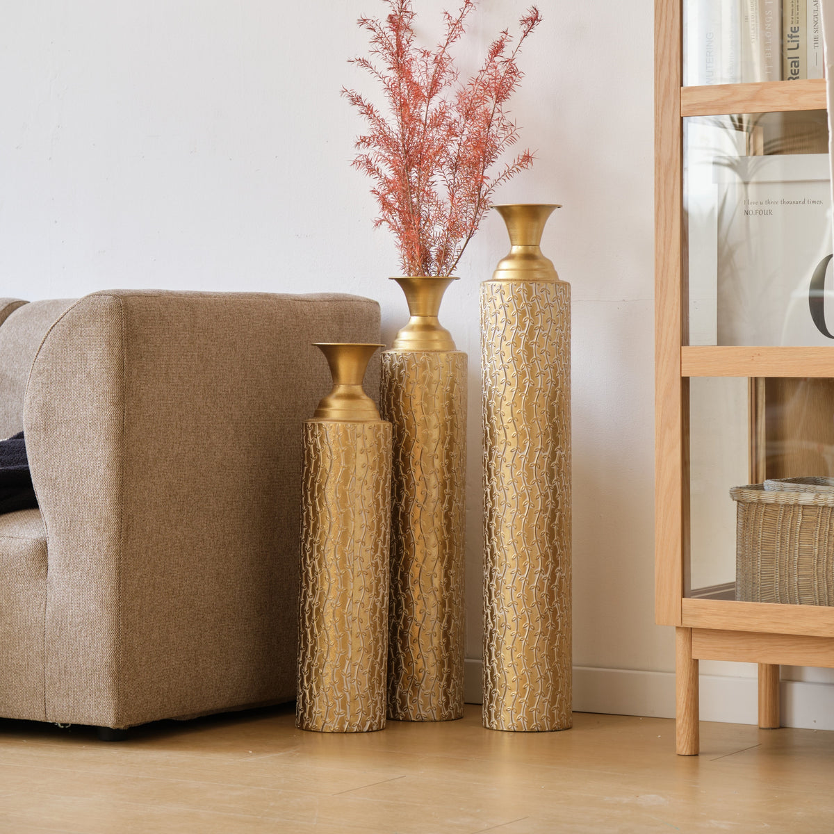 Set of three Anthony & Home Heritage Collection gold distressed metal vases with growing vine pattern for living room decor.