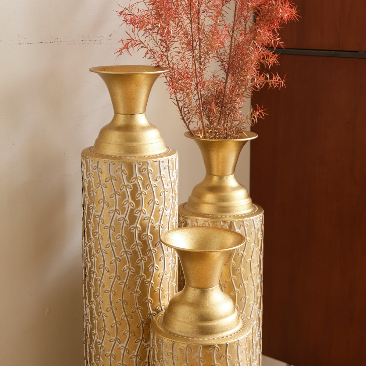 Set of three Anthony & Home Heritage Collection gold distressed metal vases with growing vine pattern for living room decor.