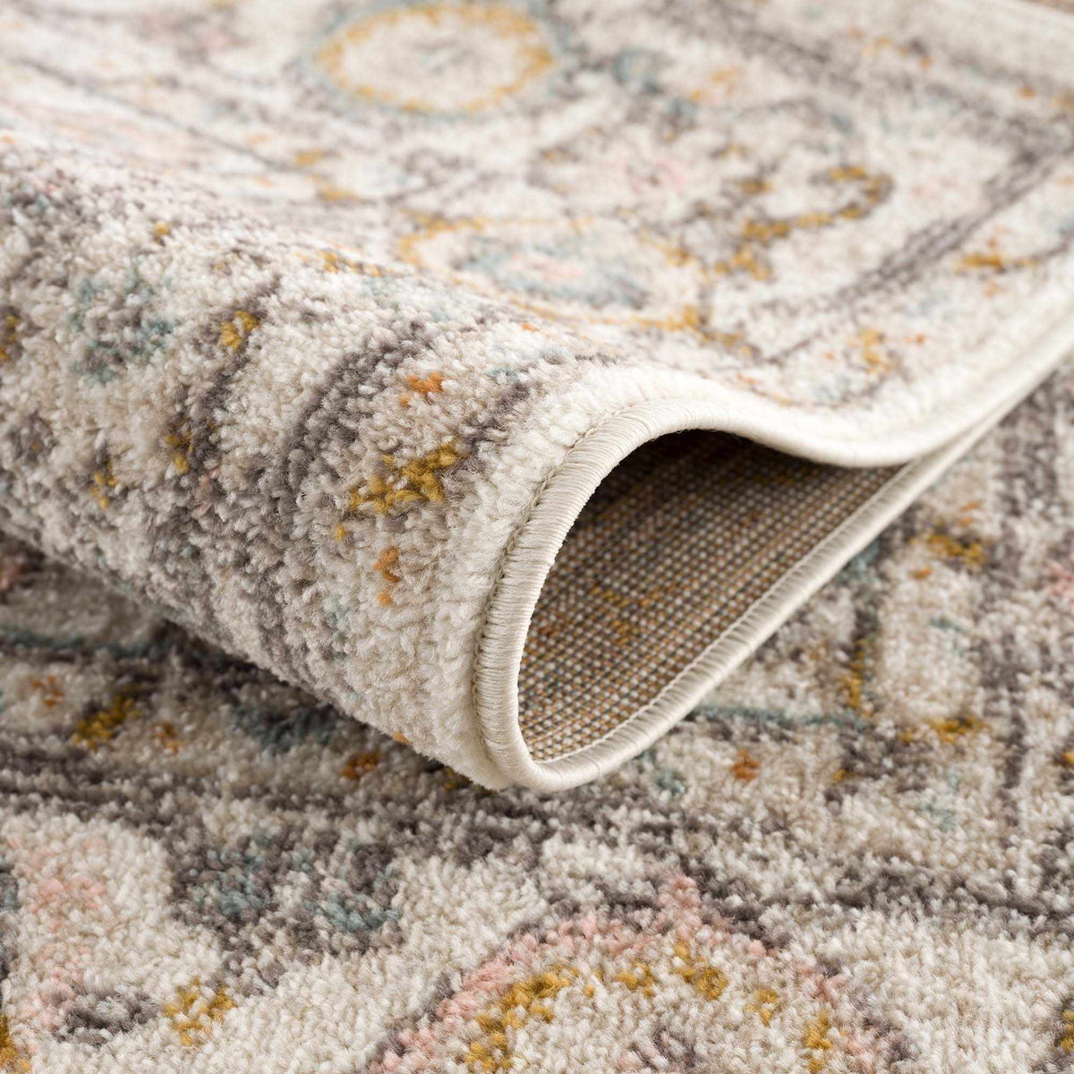 Boutique Rugs Herstmonceux area rug with a folded view, showcasing intricate patterns and soft textures in neutral tones.