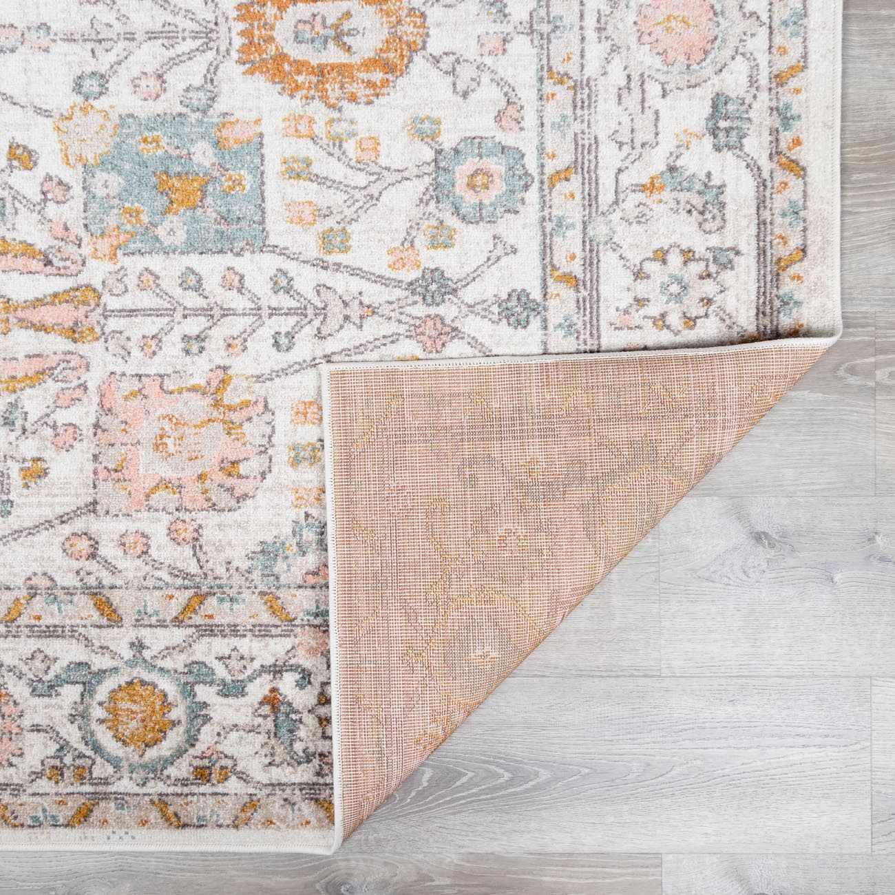 Folded Herstmonceux Area Rug by Boutique Rugs, showcasing intricate patterns and soft textures in warm tones.