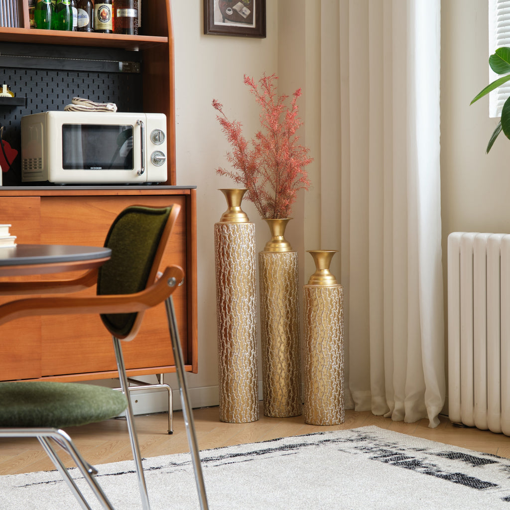 Set of three Anthony & Home Heritage Collection gold distressed metal vases with growing vine pattern for living room decor.