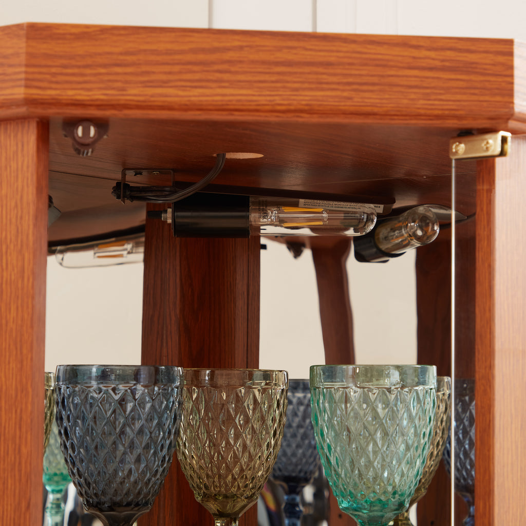 Dark oak corner lighted curio cabinet by Anthony & Home with glass display shelves and interior lighting.