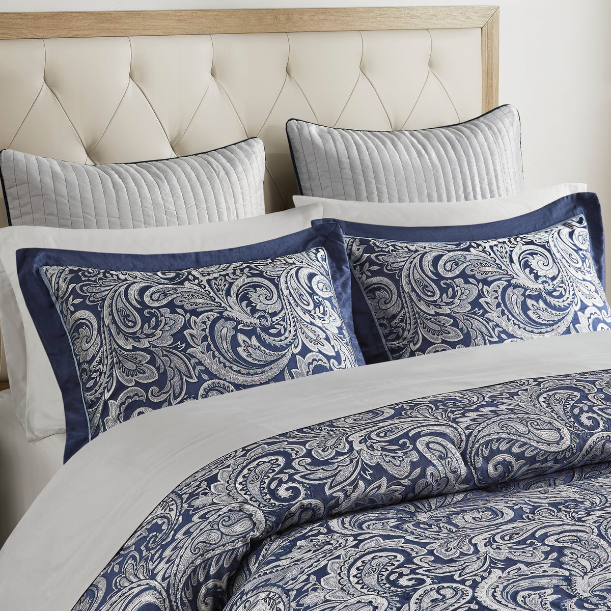 Navy jacquard cotton 12-piece Atelier Comforter Set by Anthony & Home with decorative pillow shams on a bed.