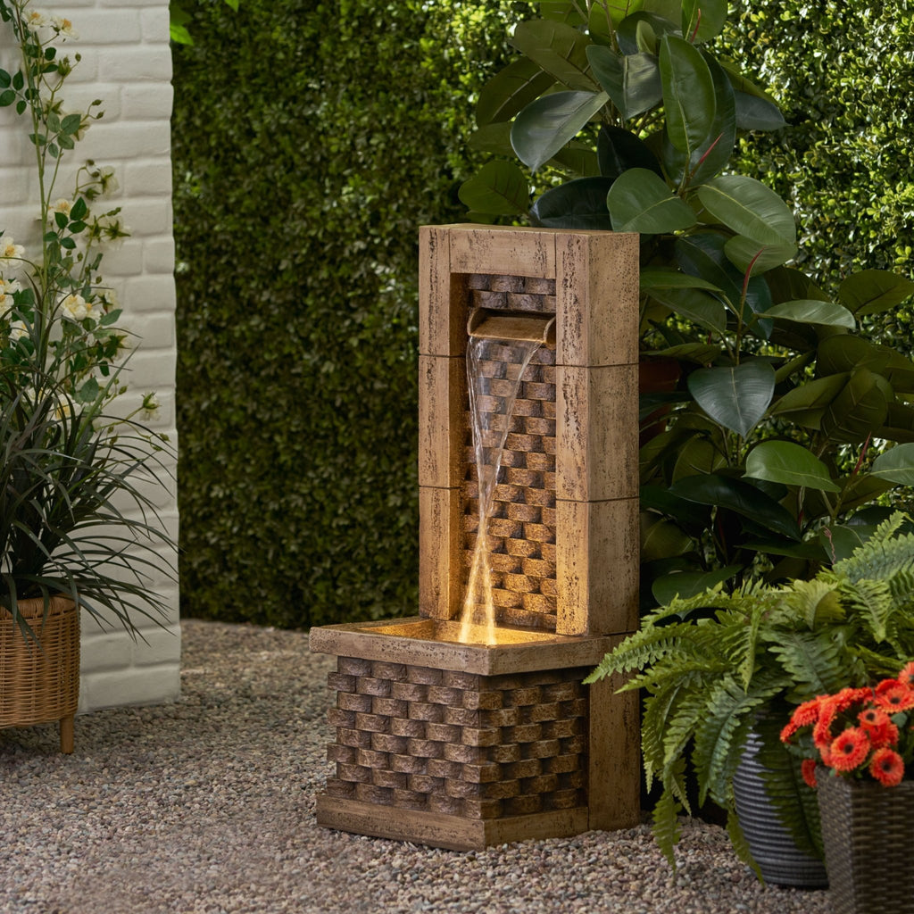 Lighted Signature Polyresin Floor Fountain by Anthony & Home featuring flowing water and decorative design in a natural outdoor setting.