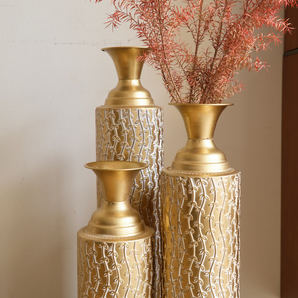 Set of three Anthony & Home Heritage Collection gold distressed metal vases with vine pattern for living room decor.