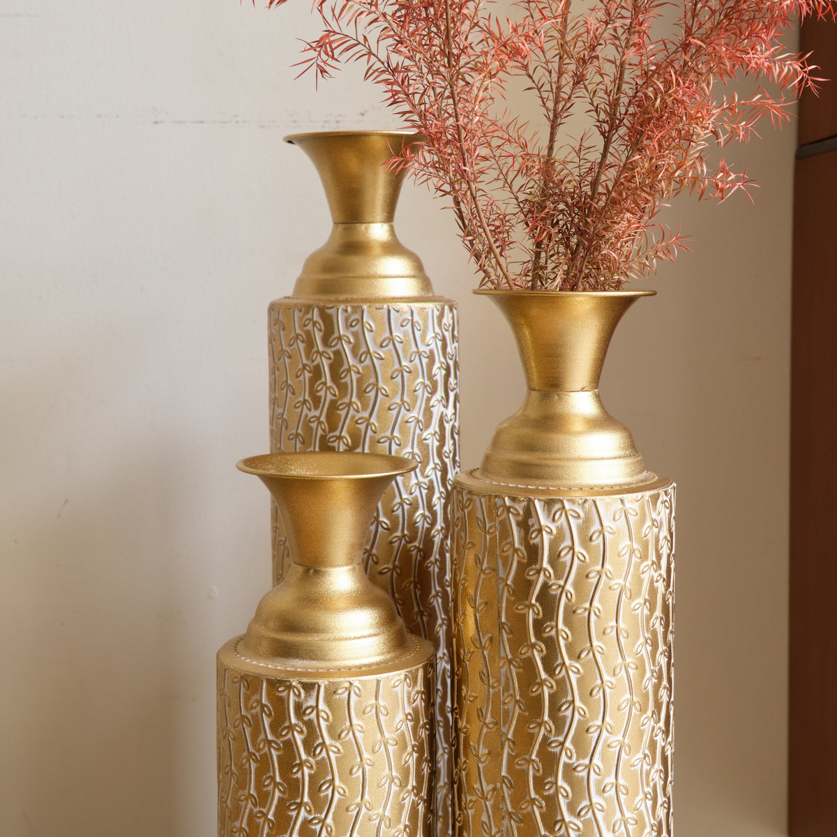 Set of three Anthony & Home Heritage Collection gold distressed metal vases with vine pattern for living room decor.
