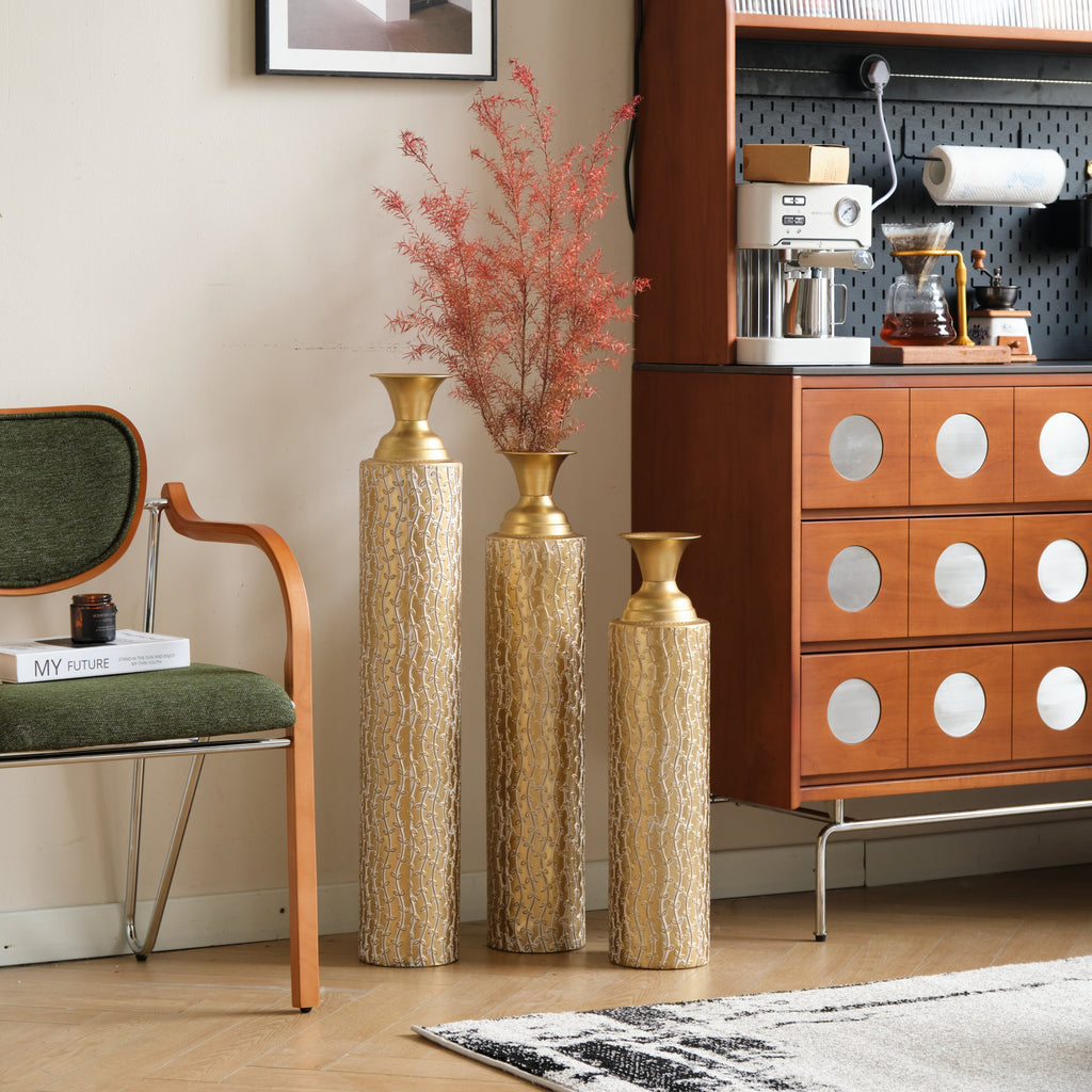 Set of three Anthony & Home Heritage Collection gold distressed metal vases with vine patterns for living room decor.