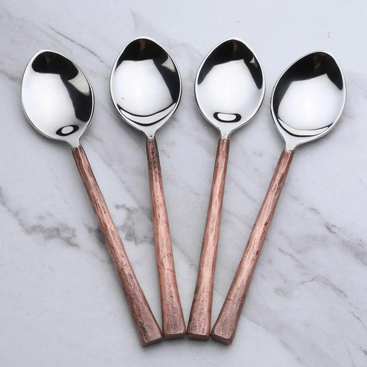 Set of four Antique Copper Sundance Table Spoons by INOX Artisans, showcasing elegant, vintage-style serving utensils on a polished surface.